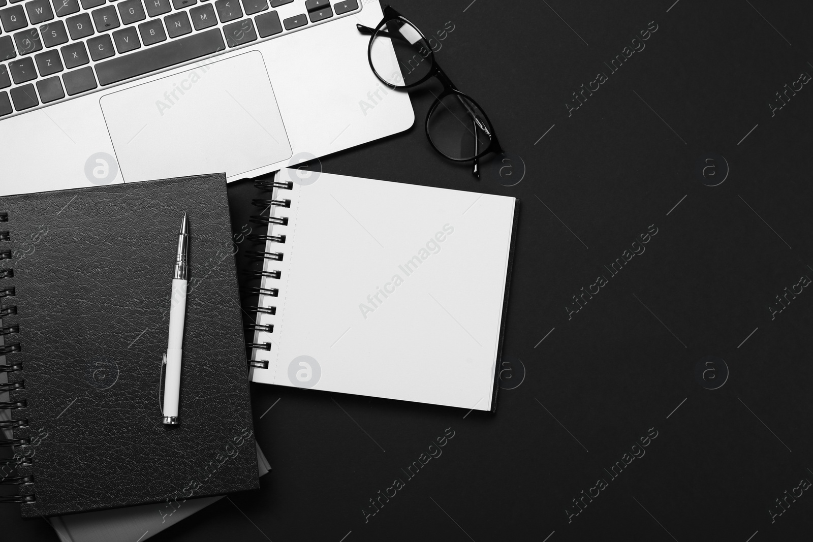 Photo of Flat lay composition with notebooks and laptop on black table. Space for text