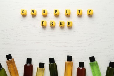 Photo of Cubes with text Cruelty Free and cosmetic products on white wooden table, flat lay. Stop animal tests