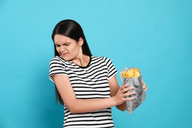 Photo of Beautiful woman refusing to eat potato chips on blue background