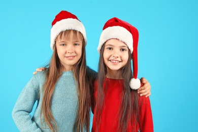 Photo of Cute little children in Santa hats on color background. Christmas celebration