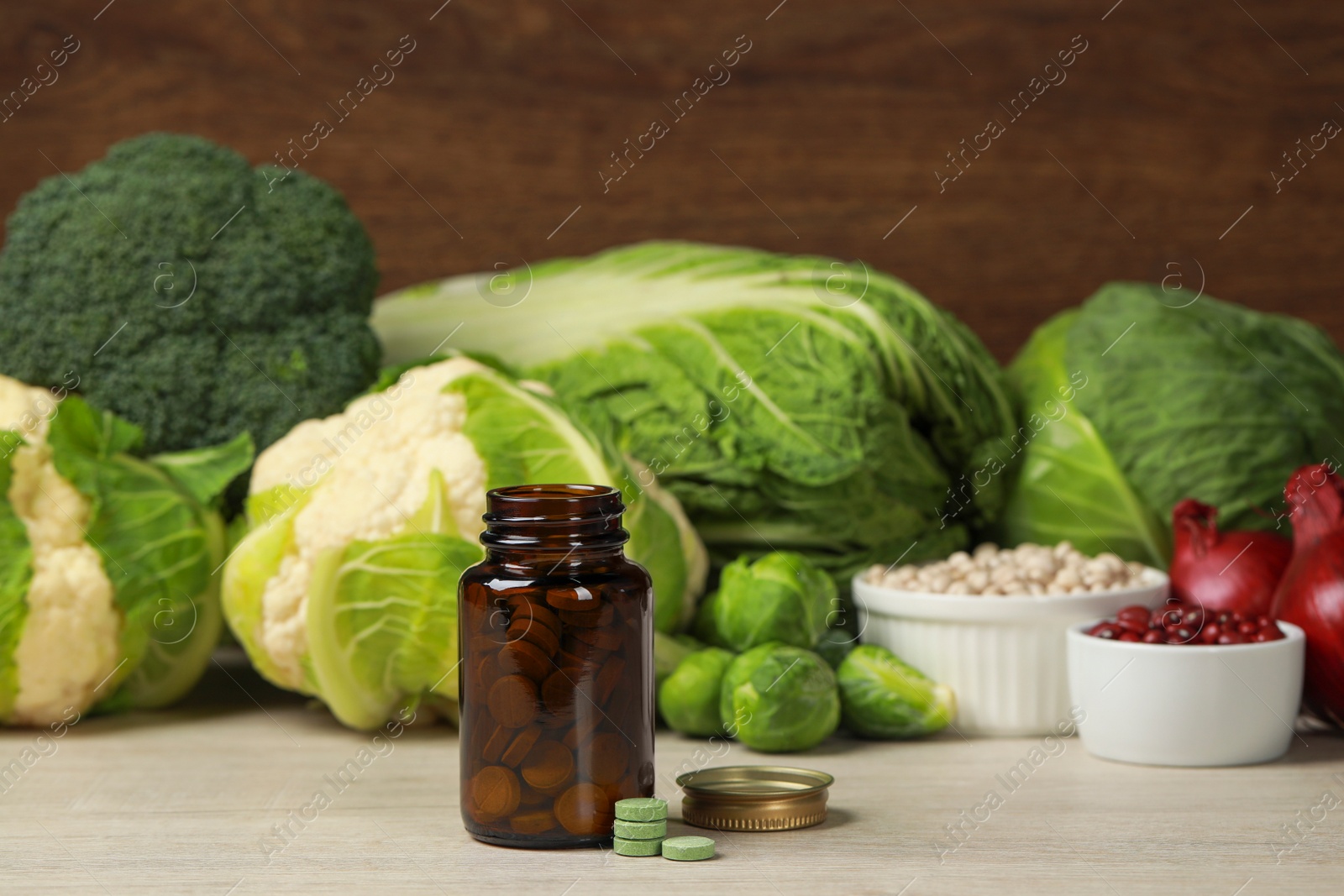 Photo of Bottle of pills and foodstuff on white wooden table. Prebiotic supplements