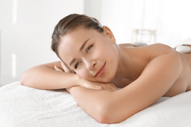 Young woman with stones on her back in spa salon