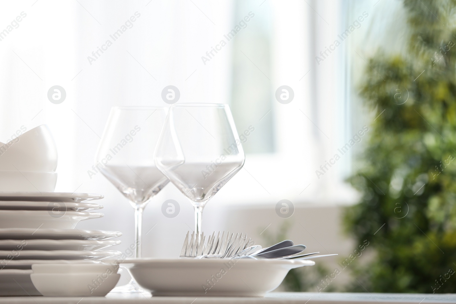 Photo of Set of clean dishware, cutlery and wineglasses on table indoors