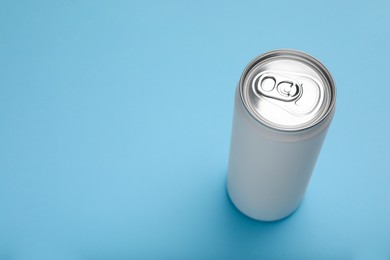 Photo of Can of energy drink on light blue background. Space for text