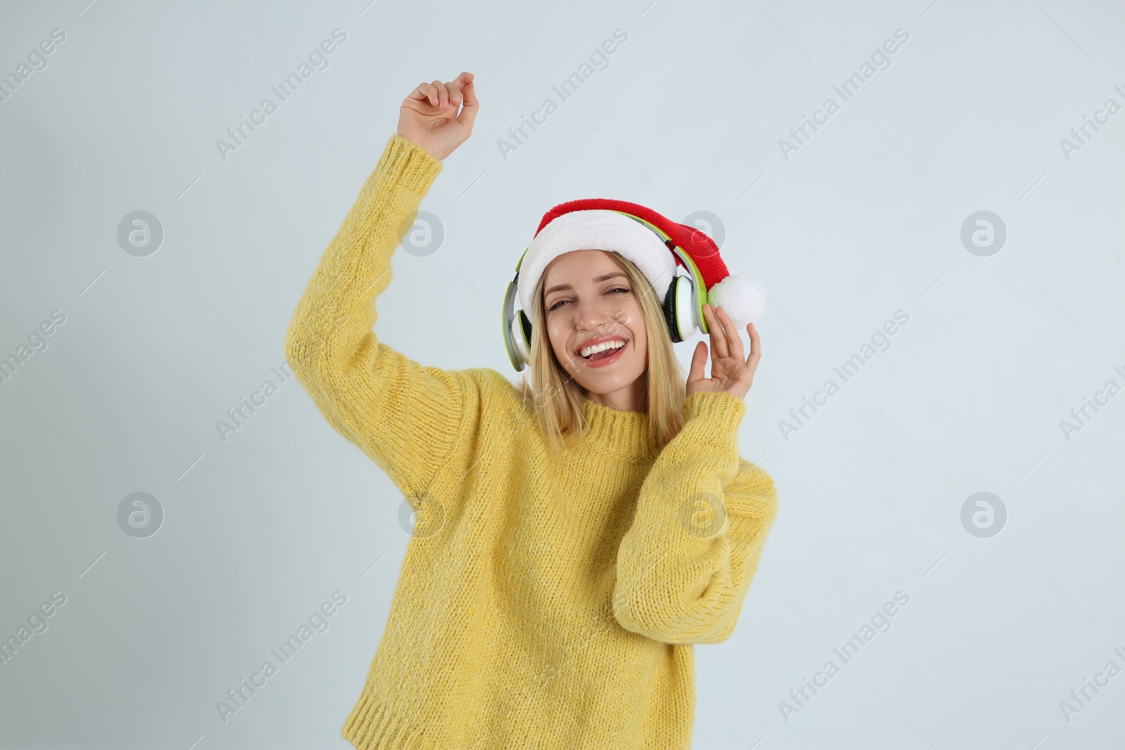 Photo of Happy woman with headphones on light grey background. Christmas music