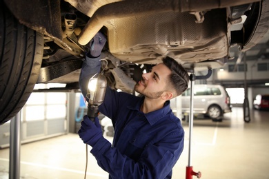 Technician checking modern car at automobile repair shop