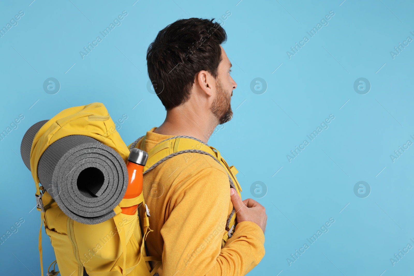 Photo of Man with backpack on light blue background, space for text. Active tourism