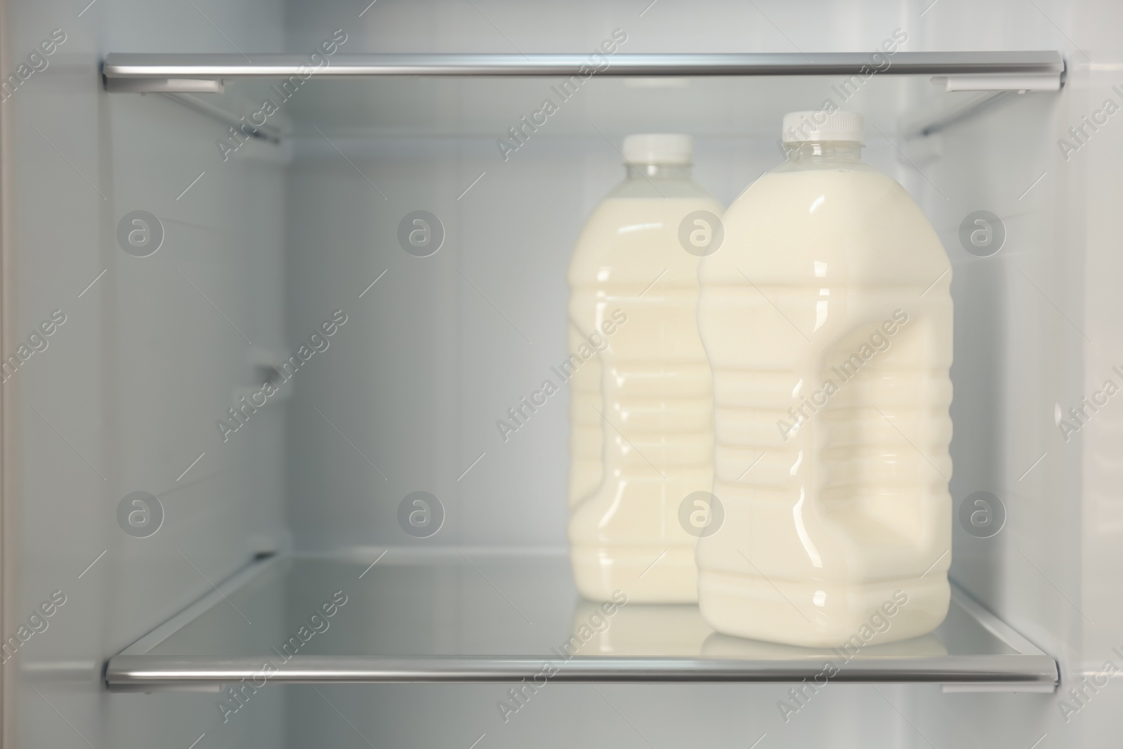 Photo of Gallons of fresh milk in refrigerator, closeup. Space for text