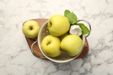 Colander with fresh apples and beautiful spring blossom on white marble table, top view