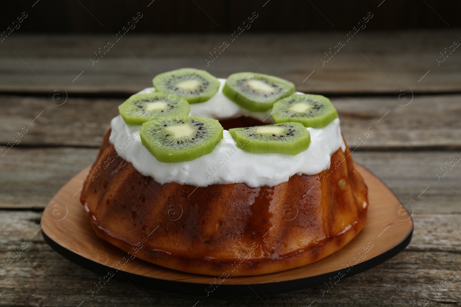 Photo of Homemade yogurt cake with kiwi and cream on wooden table