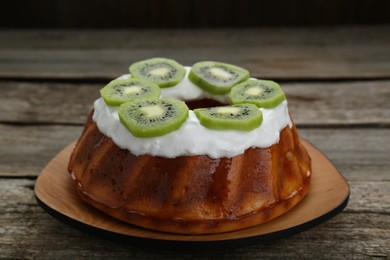 Homemade yogurt cake with kiwi and cream on wooden table