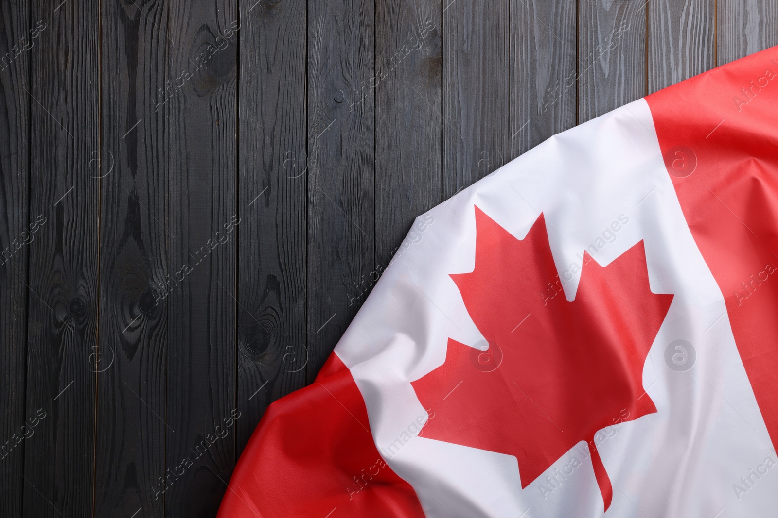 Photo of Flag of Canada on dark wooden table, top view. Space for text