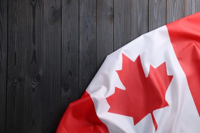 Photo of Flag of Canada on dark wooden table, top view. Space for text