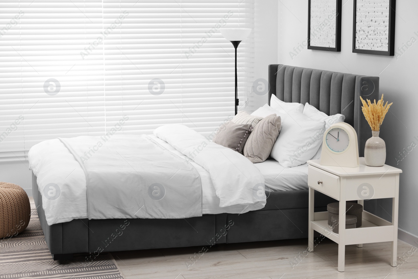 Photo of Stylish bedroom interior with large bed, bedside table and lamp