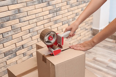 Woman packing carton box indoors, closeup. Moving day