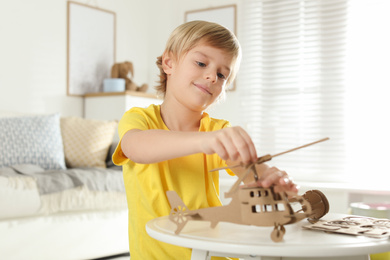 Photo of Little boy making carton toys at table indoors. Creative hobby