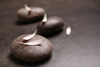 Photo of Spa stones with petals on table. Space for text