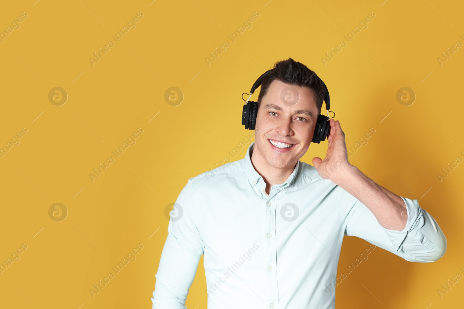 Photo of Man enjoying music in headphones on color background. Space for text