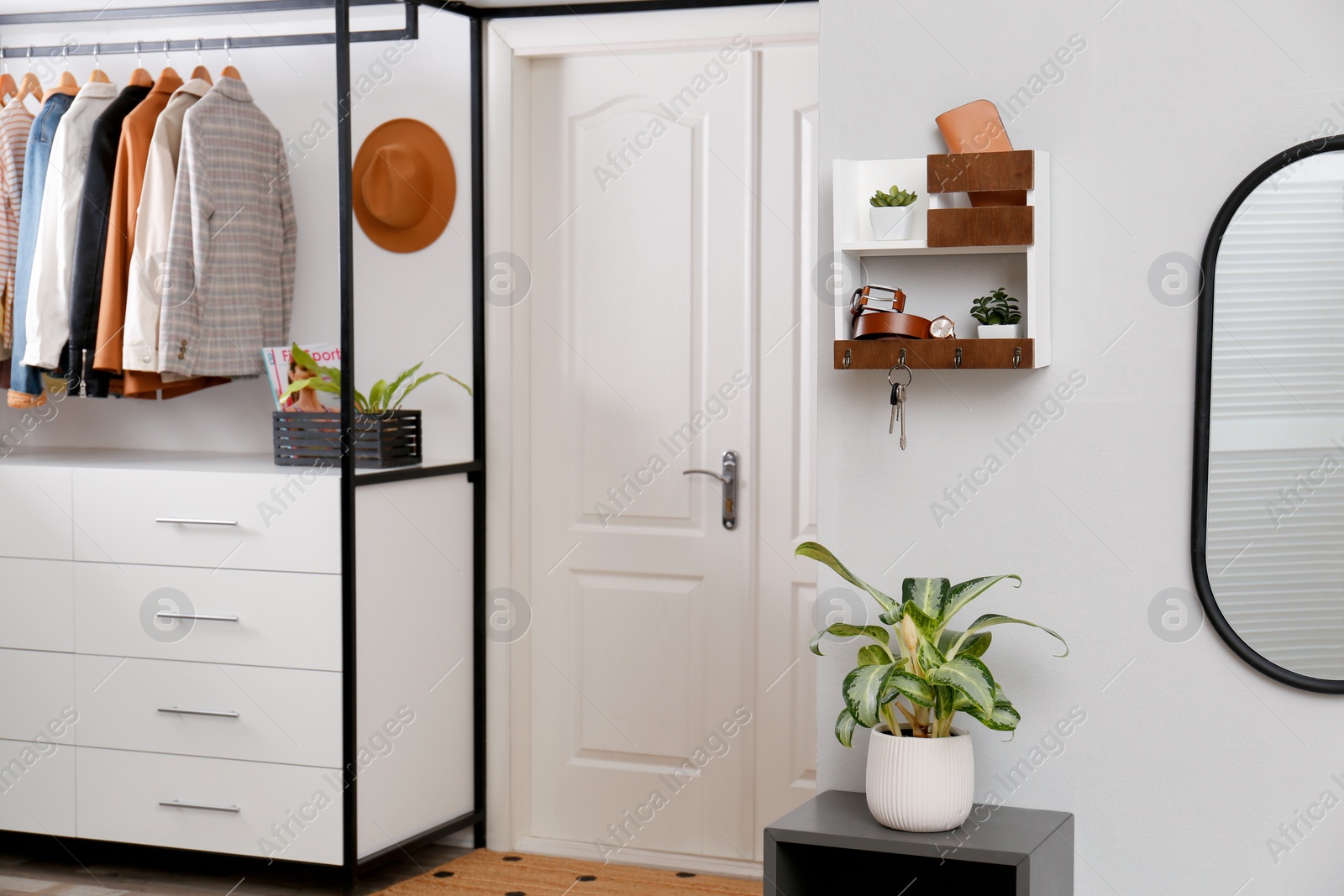 Photo of Hallway interior with stylish furniture, accessories and wooden hanger for keys on white wall