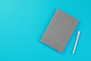 Gray notebook and pen on turquoise background, flat lay. Space for text