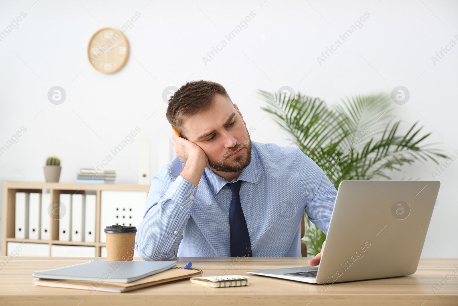 Photo of Lazy young office employee procrastinating at workplace