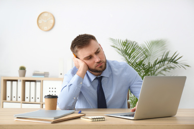 Photo of Lazy young office employee procrastinating at workplace