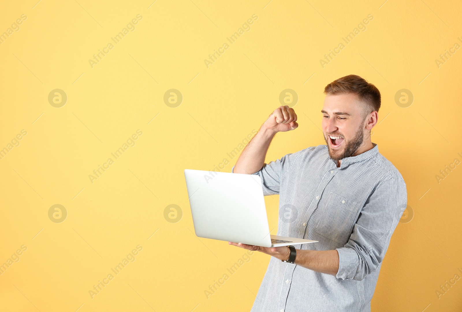 Photo of Young handsome man with laptop on color background