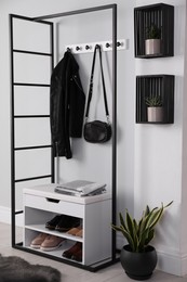 Photo of Stylish storage cabinet with different pairs of shoes near white wall in hall