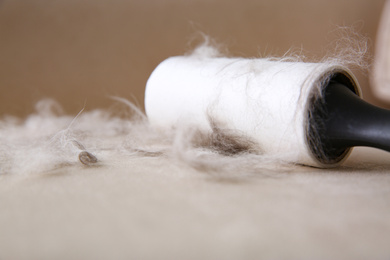 Modern lint roller and cat hair on light fabric, closeup