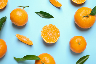 Flat lay composition with fresh ripe tangerines and leaves on light blue background. Citrus fruit