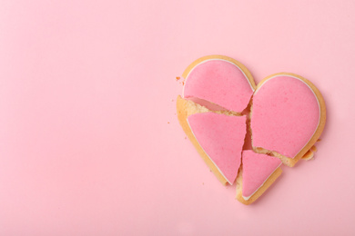 Broken heart shaped cookie on pink background, top view with space for text. Relationship problems concept