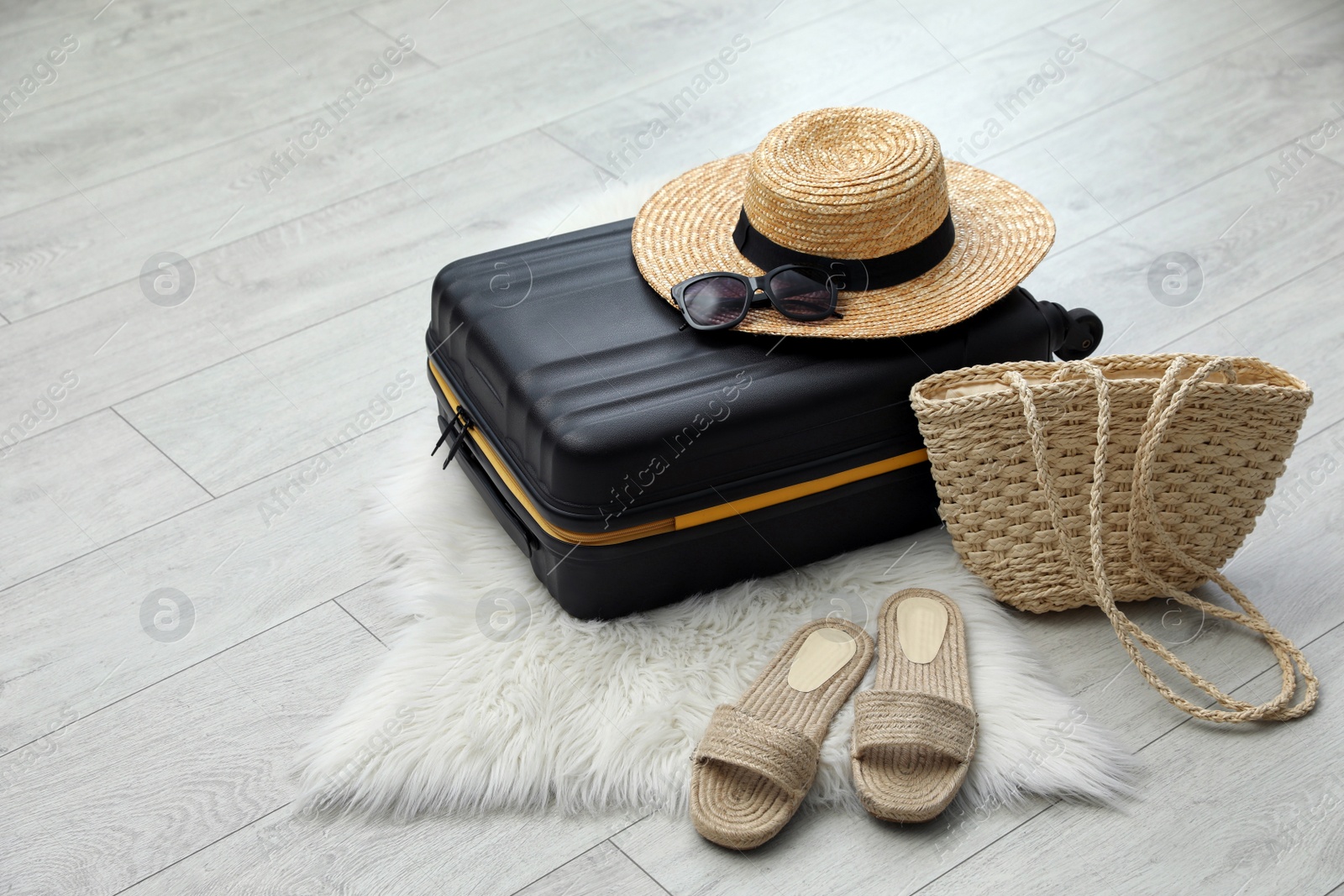 Photo of Suitcase packed for trip and summer accessories on floor indoors