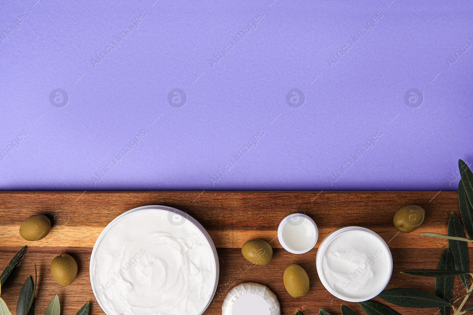 Photo of Different cosmetic products and olives on violet background, top view. Space for text