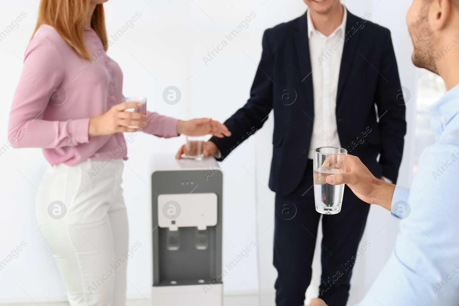 Photo of Co-workers having break near water cooler on white background, closeup