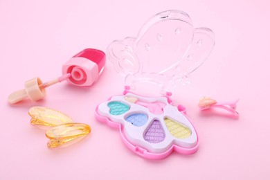 Photo of Decorative cosmetics for kids. Eye shadow palette, lip gloss and hairpins on pink background