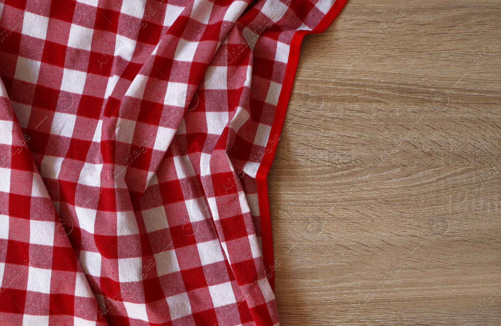 Photo of Checkered picnic cloth on wooden table, top view. Space for text