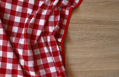 Checkered picnic cloth on wooden table, top view. Space for text