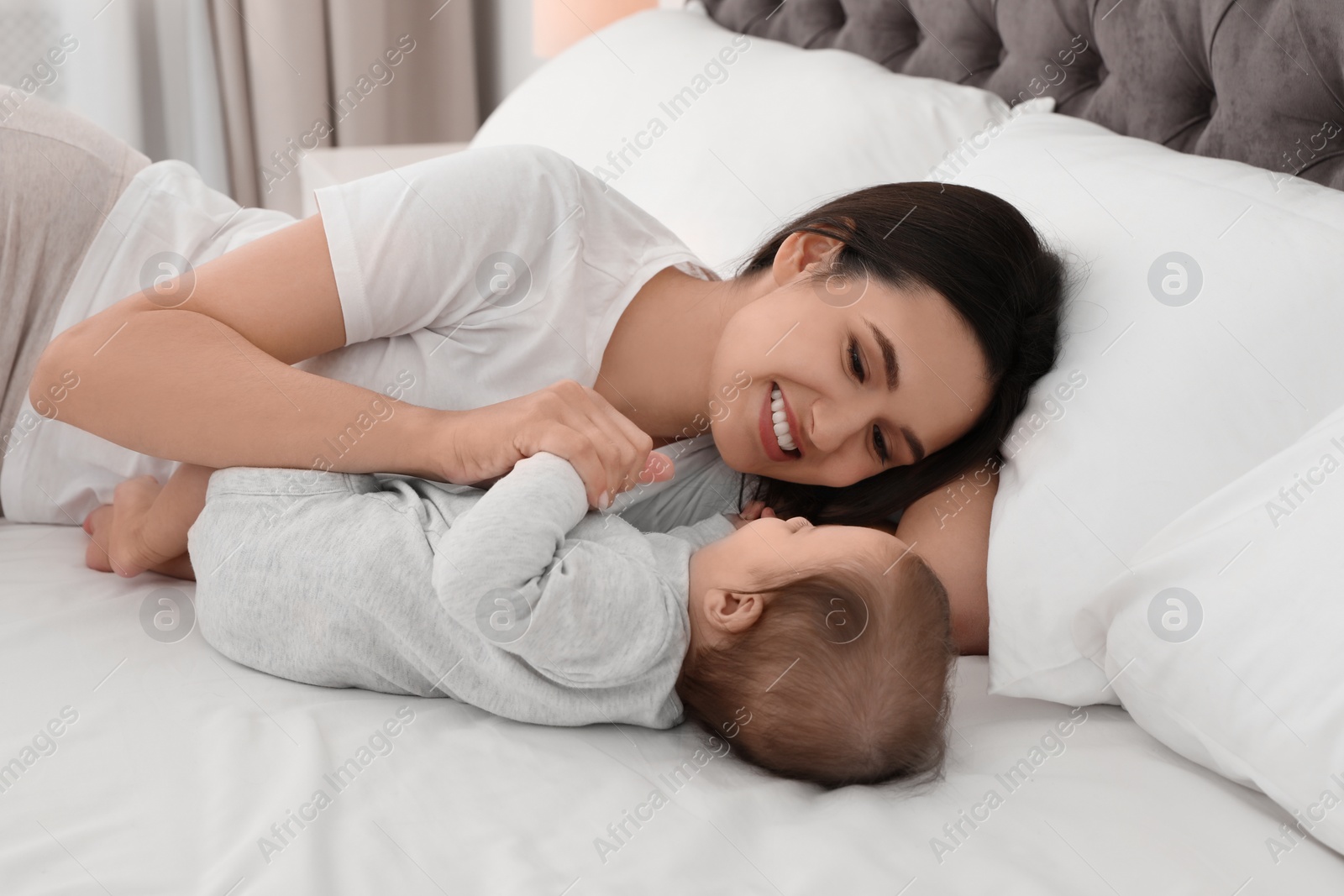 Photo of Portrait of mother with her cute baby lying on bed indoors