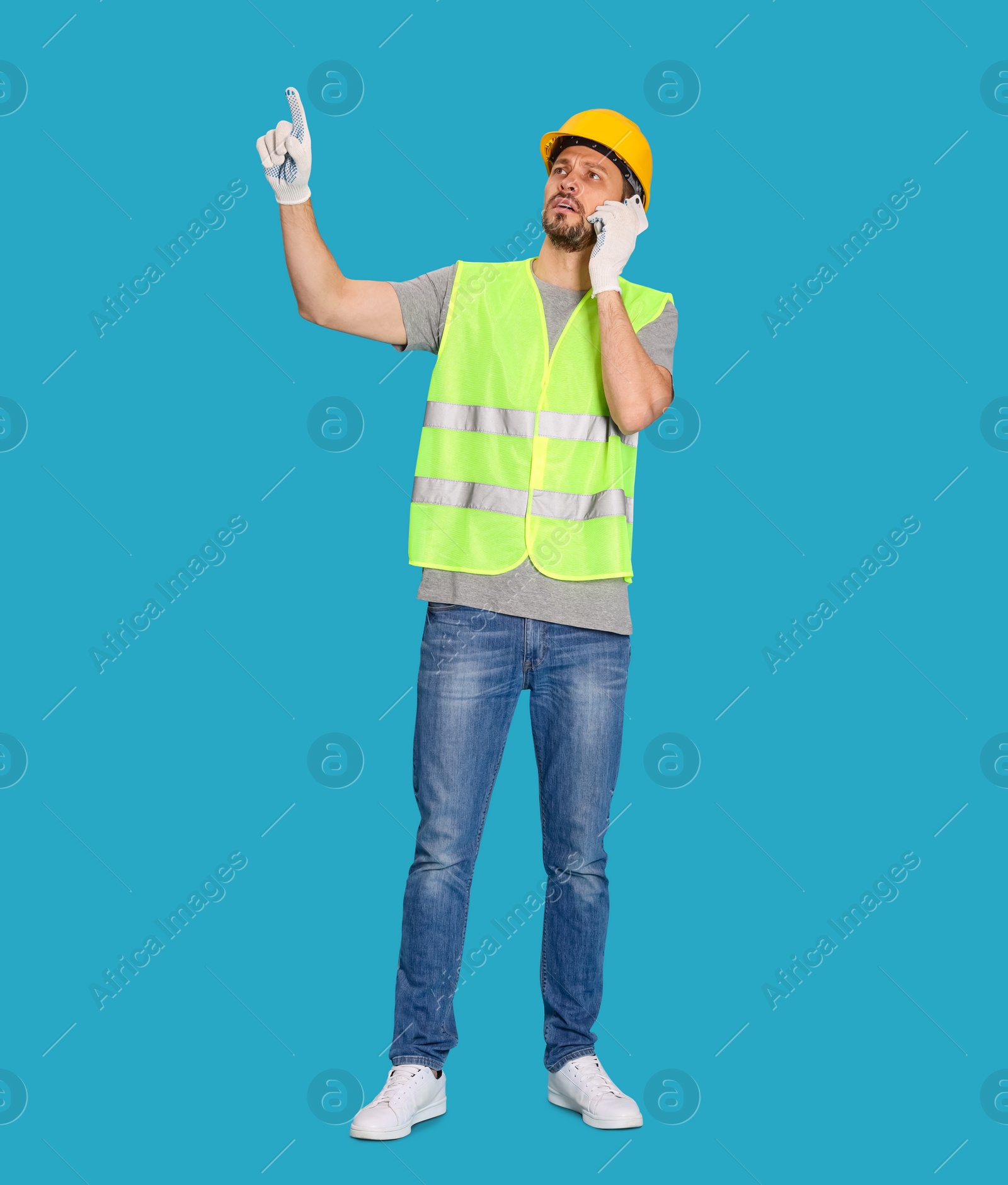 Photo of Male industrial engineer in uniform talking on phone against light blue background