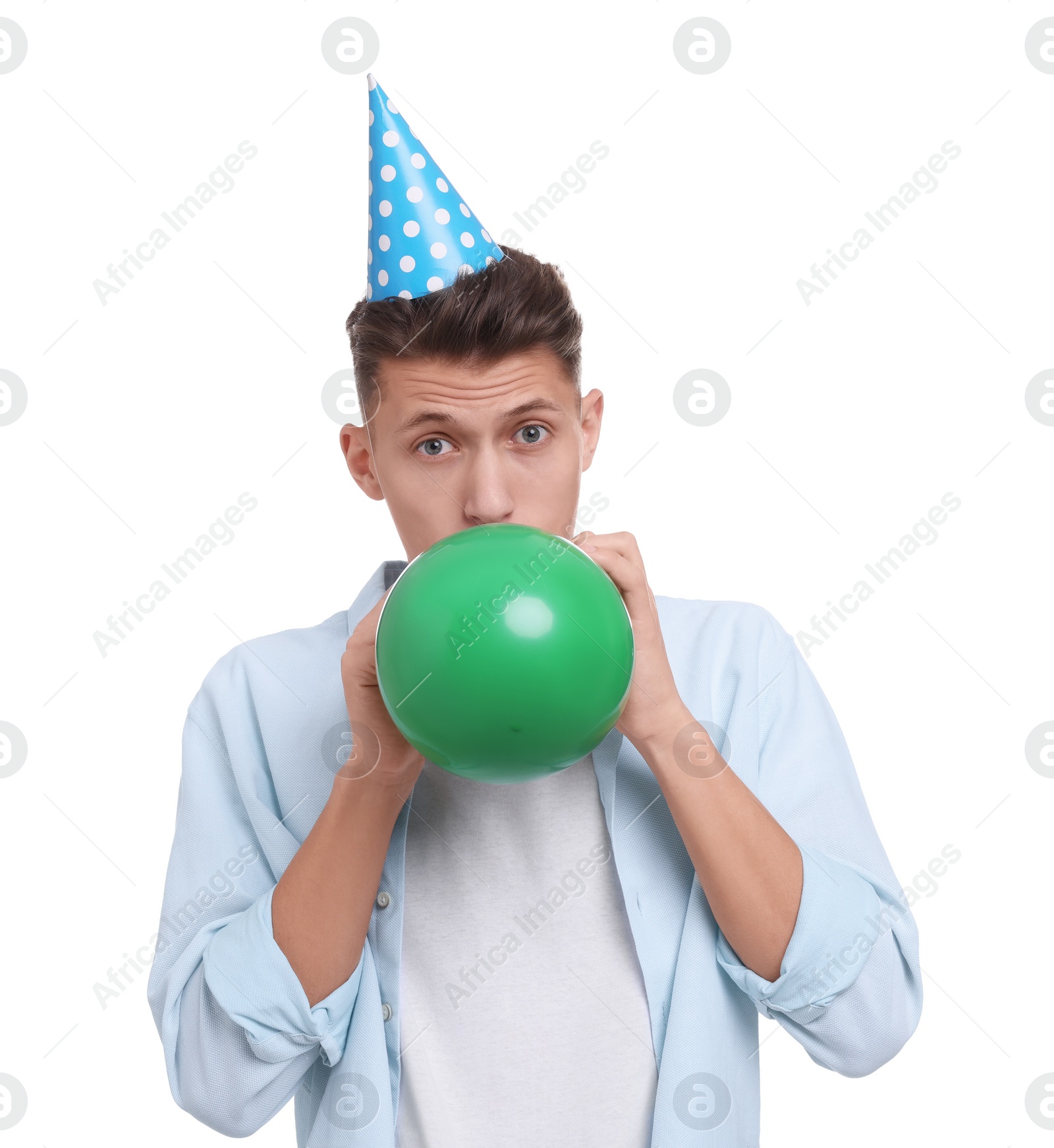 Photo of Young man in party hat inflating balloon on white background