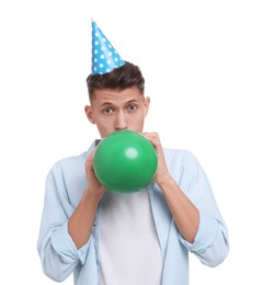 Young man in party hat inflating balloon on white background