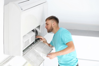 Photo of Young man fixing air conditioner at home