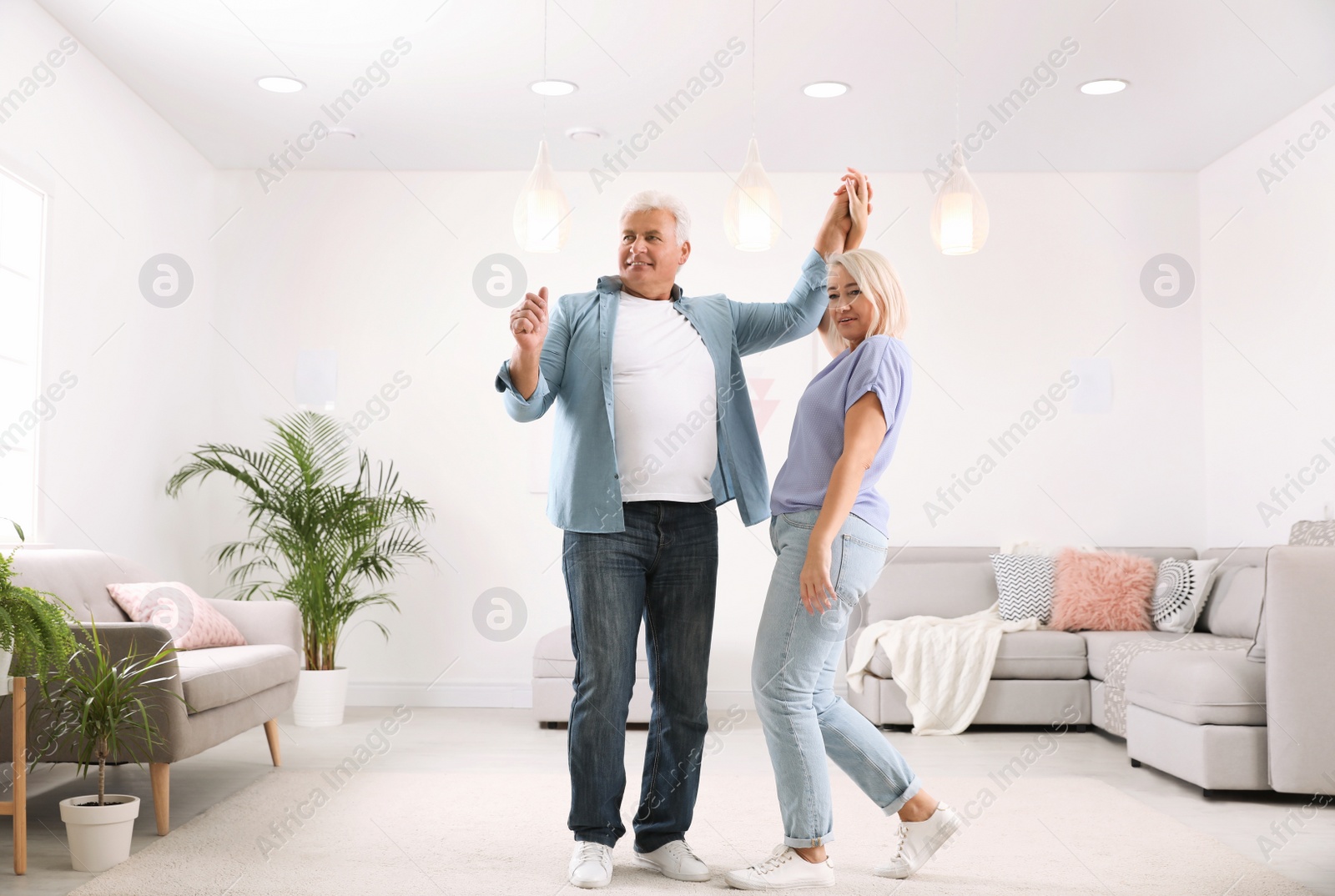 Photo of Happy mature couple dancing together in living room