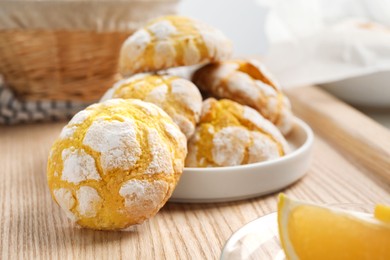 Photo of Tasty homemade lemon cookies on wooden tray, closeup