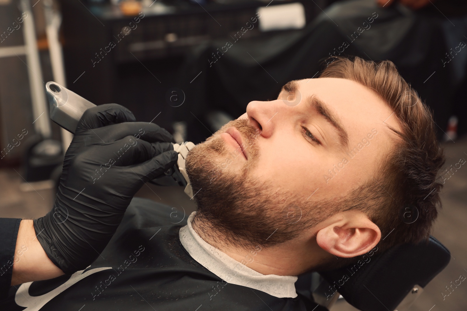 Photo of Professional hairdresser working with client in barbershop