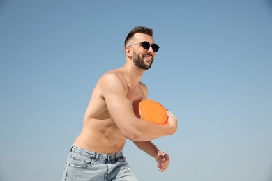 Happy man throwing flying disk against blue sky on sunny day