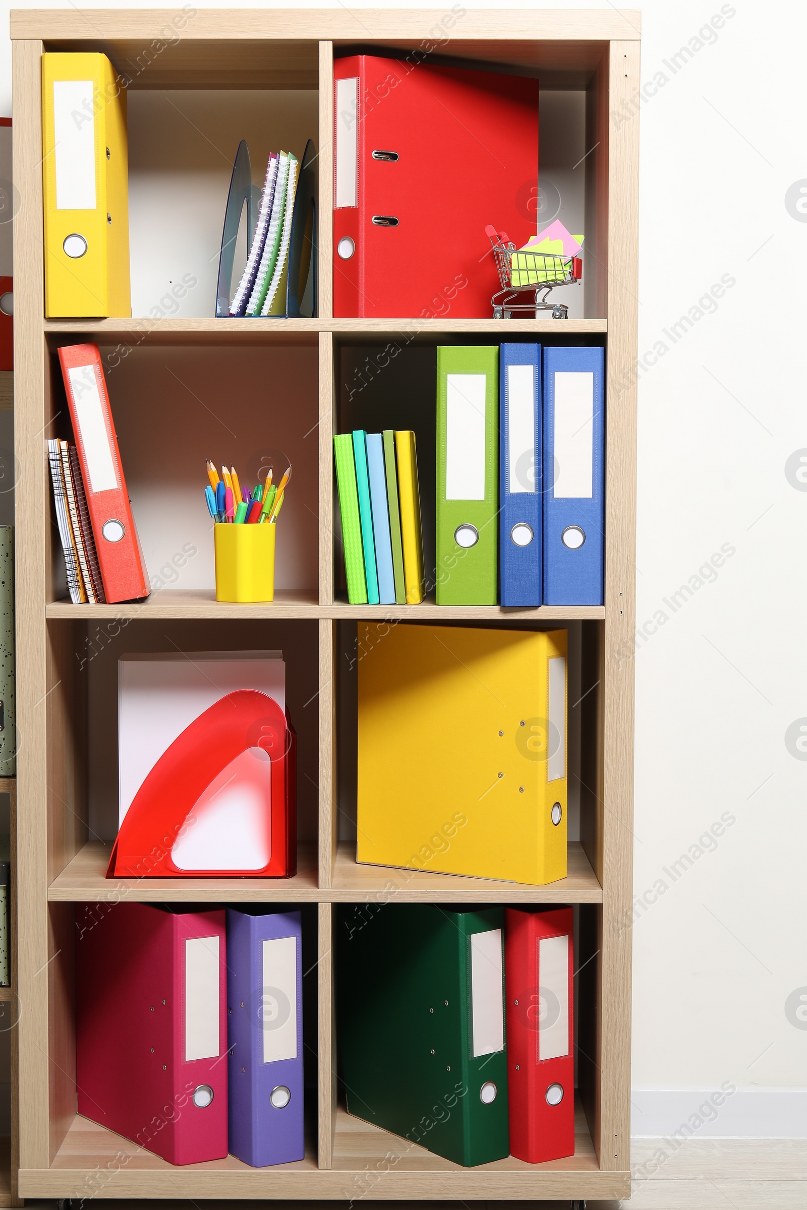 Photo of Colorful binder office folders and stationery on shelving unit indoors