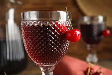 Photo of Delicious cherry wine with ripe juicy berries on blurred background, closeup