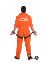 Prisoner in jumpsuit with chained hands and metal ball on white background, back view