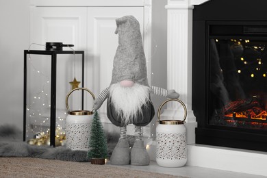 Photo of Cute Scandinavian gnome and other Christmas decorations in room with near fireplace